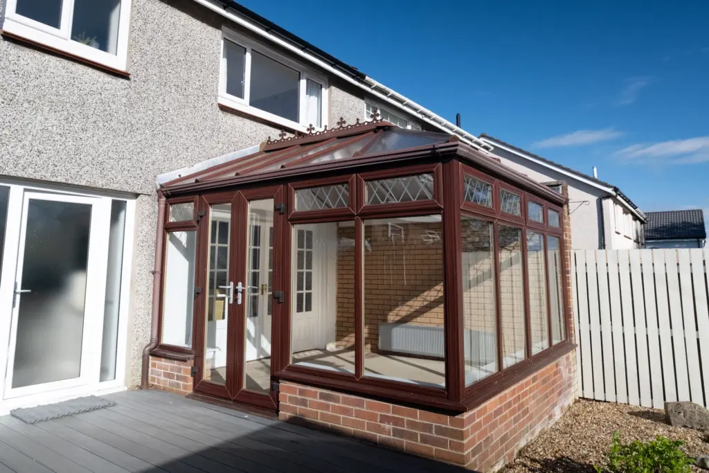 Brown conservatory frames and polycarbonate roof before replacement