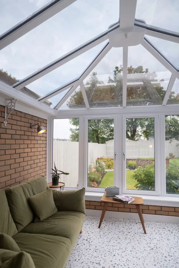 Finished conservatory lounge with full-height white frames and garden view
